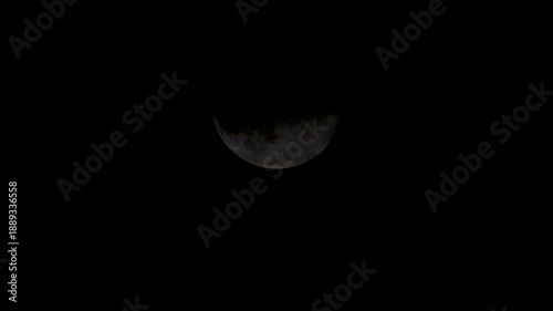 Moon partially covered by clouds during a night sky observation in a quiet location