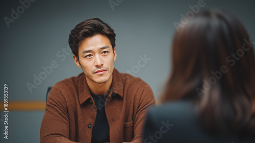 Professional Asian man in business meeting or job interview. Corporate office career consultation with HR person. Listening attentively. Serious communication concept.