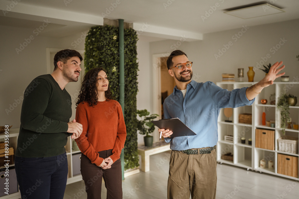 Obraz premium Real estate agent showing potential home to young couple