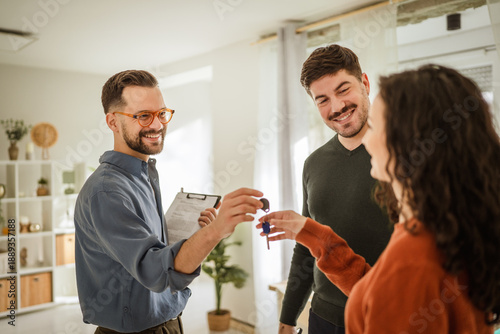 Foto Realtor giving new home keys to smiling couple