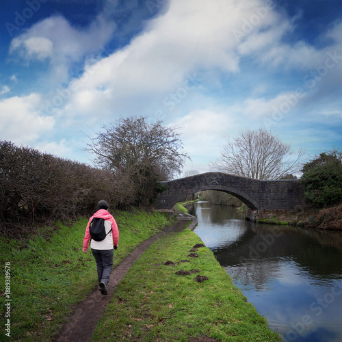 Картината върху платно Woman walking along a canal towpath in Winter