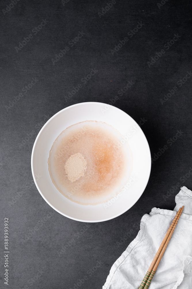 Fotografie Instant dry yeast sprinkled on warm water, dry yeast granules on water