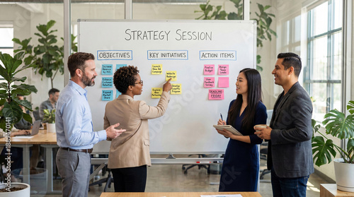 Business strategy session meeting with diverse team planning objectives and key initiatives using sticky notes on whiteboard in modern office