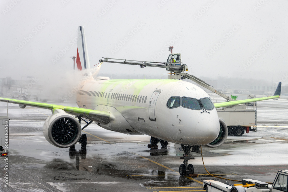 Naklejka premium De-icing An Aircraft On The Ground With An Elevated Arm In Snow At The Airport