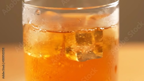 Macro shot of refreshing cold beverage with melting ice cubes in a transparent glass, perfect for summer thirst quenching or happy hour cocktail imagery.
