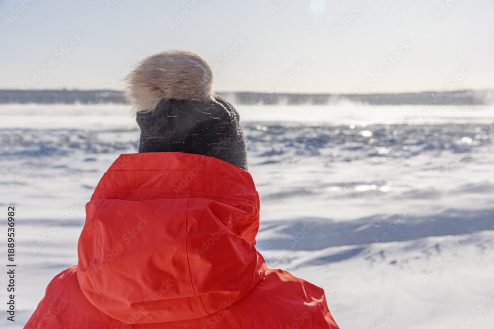 Fototapeta premium Woman outdoors in Winter looking out over a freezing Saint Lawrence River.
