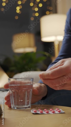 Wallpaper Mural Man taking red pill and glass of water while sitting on sofa in living room at home. Person taking medication to relief pain. Concept of medication, health care and treatment Torontodigital.ca