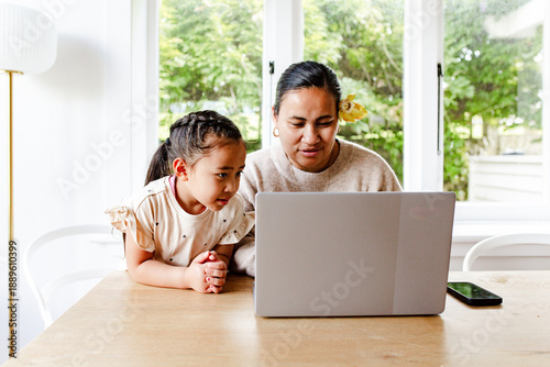 Young girl watching mum attentively while working on her laptop