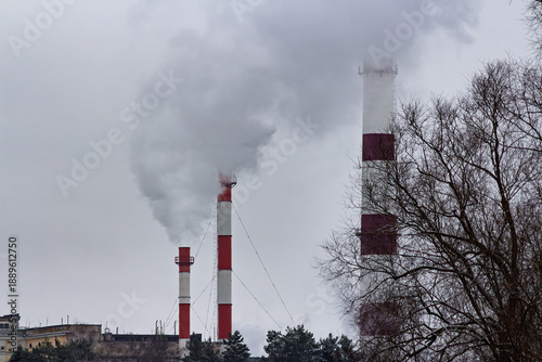 Obraz na płótnie Towering striped industrial chimneys belch vast plumes of steam against a dull w