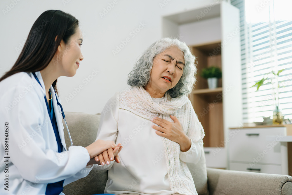 Obraz premium Female doctor supporting elderly woman at home during medical visit. Senior healthcare, home care, patient support, wellness, trust and professional medical assistance concept.