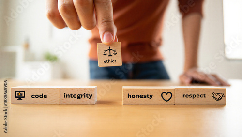 Person placing wooden block with ethics symbol on table with integrity and respect blocks