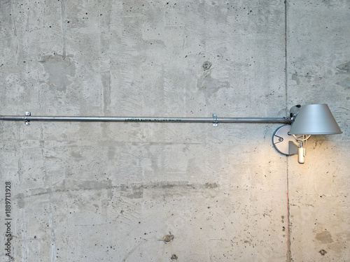 Tableau sur toile Modern wall-mounted lamp with silver shade on a raw concrete wall background, loft interior design