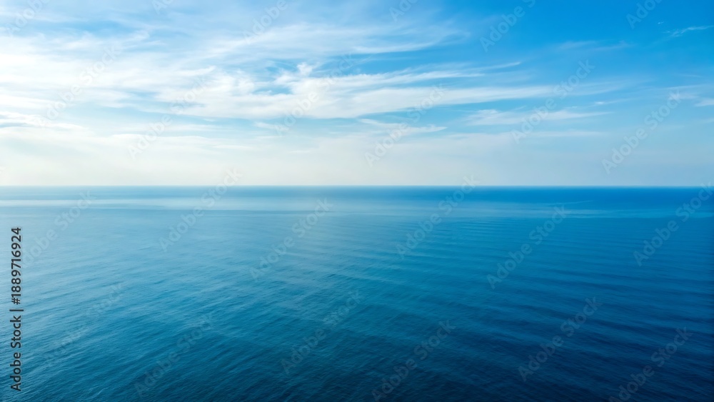 Obraz premium Expansive ocean horizon under a clear blue sky with wispy white clouds, serene and tranquil natural landscape.