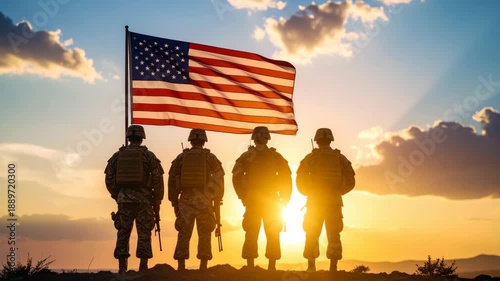 Four soldiers in silhouette stand facing a waving American flag at sunset