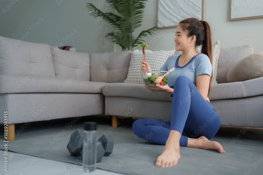 Obraz premium Young woman enjoying healthy salad after home workout