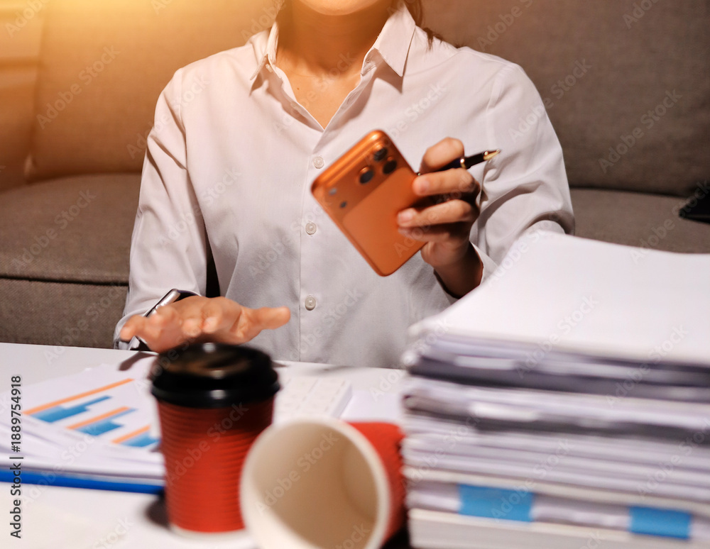 Fototapeta premium Exhausted female employee experiencing burnout while working overtime. A tired professional woman under pressure with a headache.