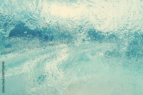 Fotografija A stream of water running down a flat light turquoise glass surface