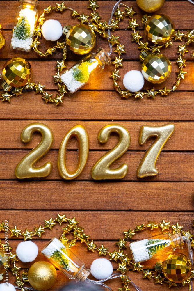 Obraz premium Happy New Year wooden numbers 2027 on cozy festive brown wooden background with sequins, snow, lights of garlands. Greetings, postcard. Calendar, cover