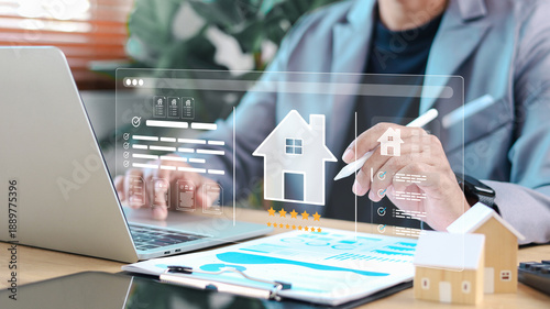 Real estate agent analyzing digital property platform on laptop with virtual house icon, rating stars, and documents. Concept of property evaluation, smart real estate, and online housing service.