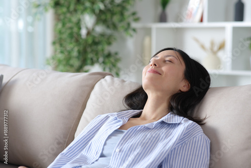 Free Download Relaxed asian woman resting on a comfortable couch - GFXLoad