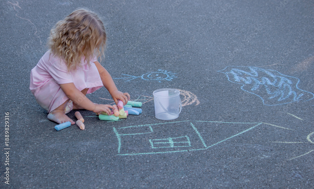 Naklejka premium Creative little girl drawing with colorful chalks on asphalt outdoors