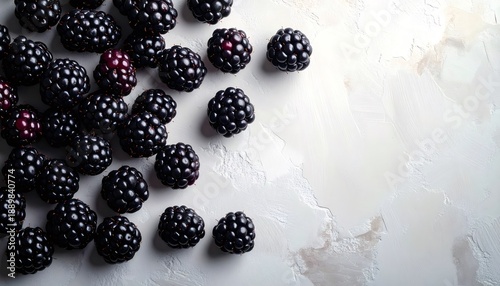 Fresh organic blackberries scattered on textured white background