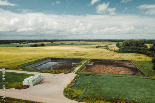 Agricultural lagoons beside crop fields viewed from drone. Rural farming infrastructure, waste storage, and the relationship between food production and environmental management.