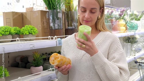 Woman smelling scented candle while holding decorative object in store