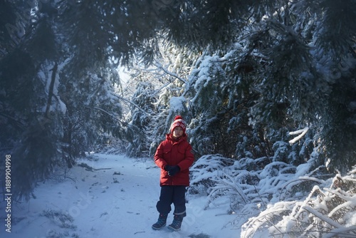 boy in red jacked walking in winter forest
