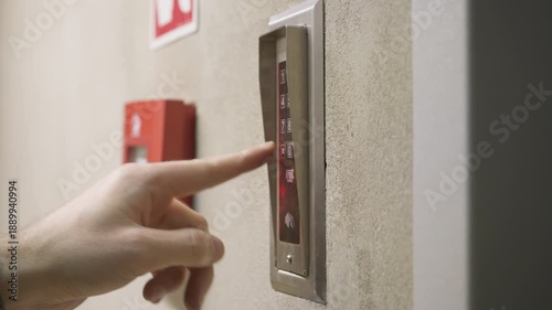 Finger pressing numbers on digital keypad intercom to enter access code. Sound of button beeps. Electronic security entry system on building wall. Door access control and security technology.