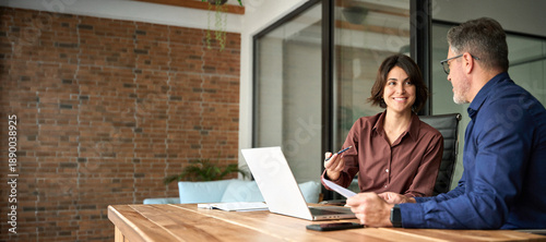Two happy executives working on laptop discussing financial documents at meeting. Professionals team talking planning project at work. Attorney or bank manager consulting client investor in office.