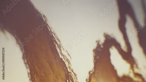 Fascinating abstract pattern with golden brown liquid shapes flowing dynamically against a brighter background, creating a visually engaging and textured surface