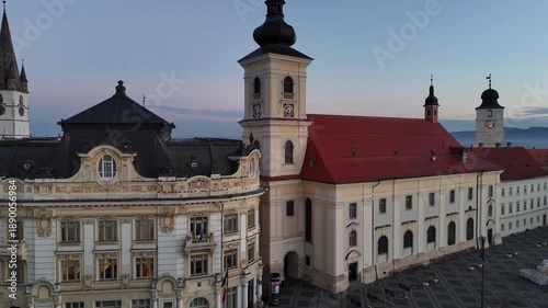 30 october 2024, Sibiu, Romania. Sunrise, Forward drone flight at Piața Mare, main square, to Holy Trinity Roman Catholic Church. Beautiful  touristic must-see destination. Historical buildings, trave
