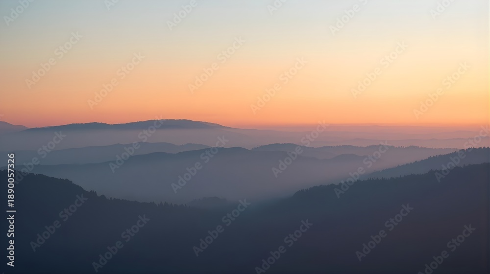 Fototapeta premium Foggy mountain range at sunrise with layered silhouettes, soft pastel sky and mist, calm cinematic nature background, minimalist landscape photography