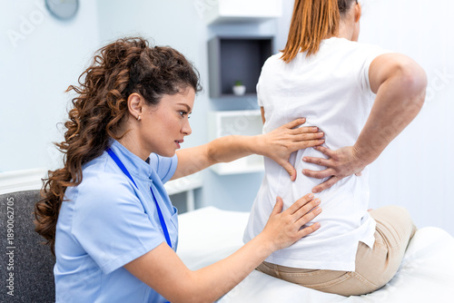 Schilderij op canvas A female healthcare professional examines the lumbar spine and lower back of a patient sitting on a treatment bed, focusing on pain relief, spinal health, and orthopedic injury rehabilitation