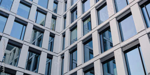 Tableau sur toile Modern office building facade with glass windows and metal panels forming a clean geometric pattern, contemporary architecture background for corporate and design use