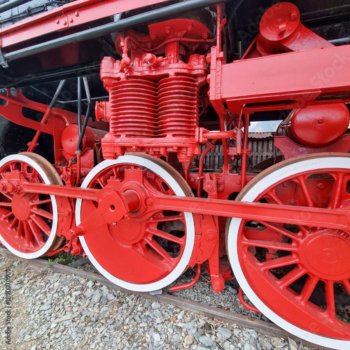 Red driving wheels and side rods of a vintage steam locomotive