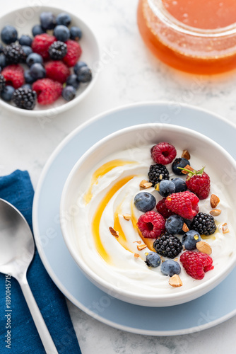 Greek yogurt bowl with raspberries, blueberries, blackberries, almonds, and honey. A healthy delicious breakfast.  Selective focus