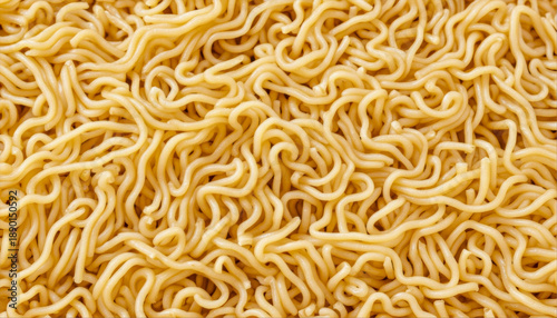 Close-up of cooked yellow ramen noodles from above. The angle is from above, showing the tangled strands of pasta under bright, even lighting.