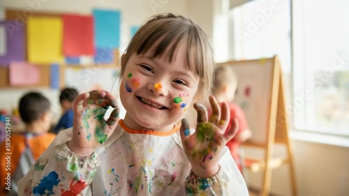 cheerful caucasian girl with down syndrome showing colorful painted hands. happy child with disability enjoying art class in kindergarten. education, inclusion concept.