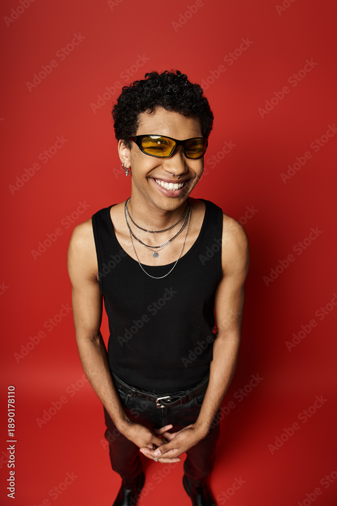 Obraz premium Stylish young man with curly hair and vibrant sunglasses poses in a bold studio setting