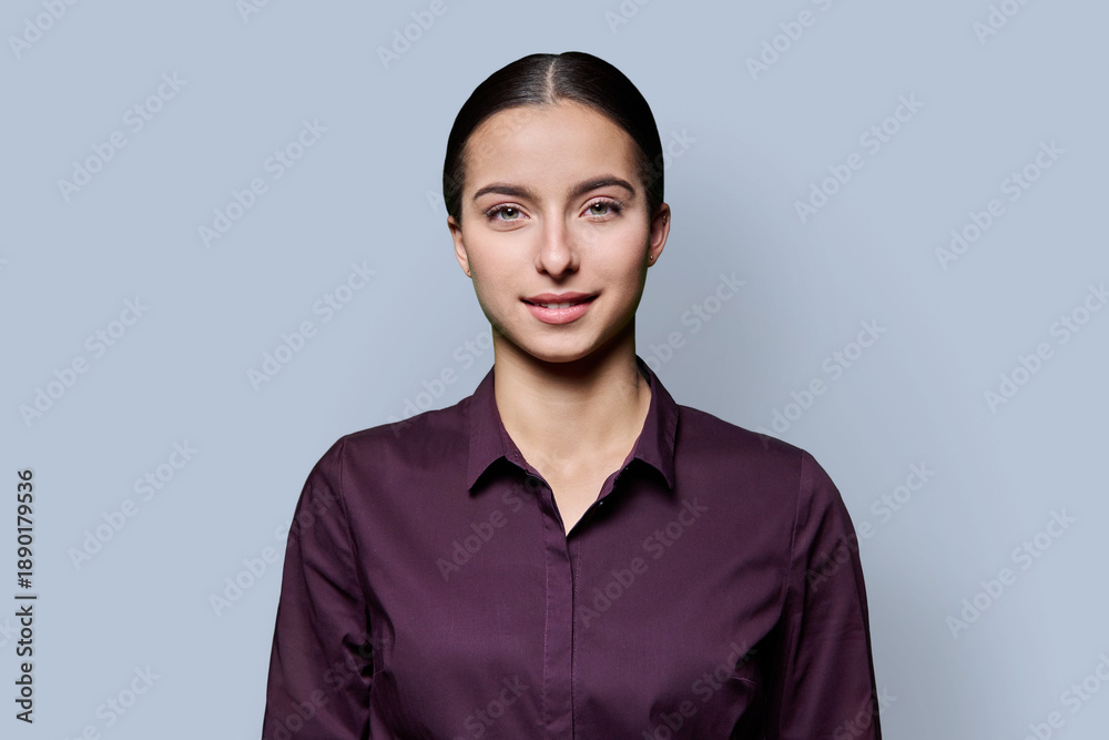 Fototapeta premium Portrait of beautiful smiling teenage woman against gray studio background