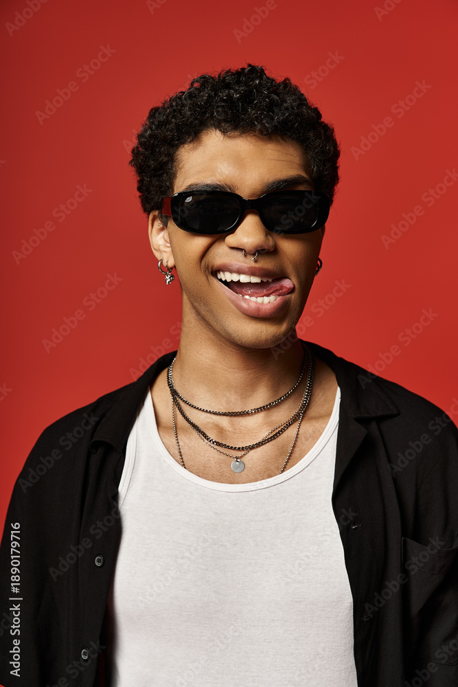 Obraz premium Charming young man showcases trendy sunglasses and playful personality in studio setting