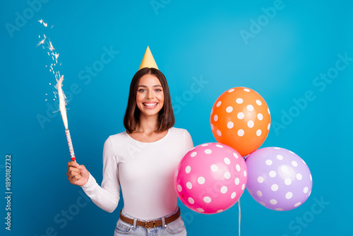 Photos Young woman celebrates birthday with balloons and sparkler on a bright blue back