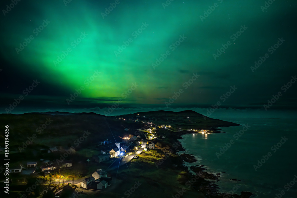 Fototapeta premium The Aurora Borealis, the northern lights, showing up above Portnoo harbour in County Donegal, Ireland