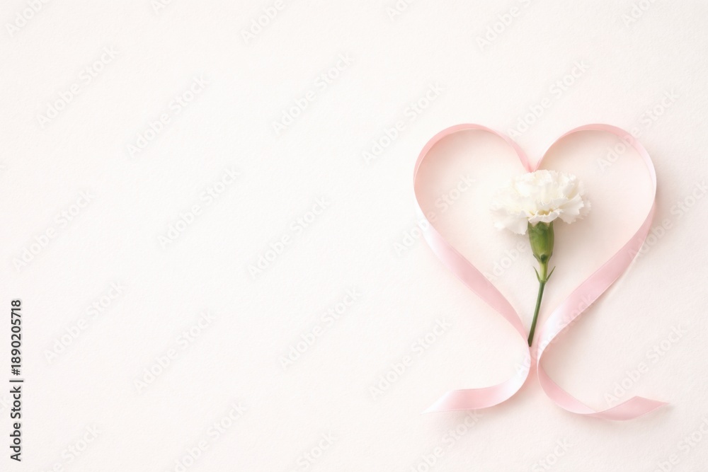Fototapeta premium Delicate heart shape with a flower and ribbon on a soft background.