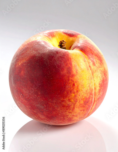 Close-up Ripe peach with yellow/red skin, slight fuzz, and a stem remnant