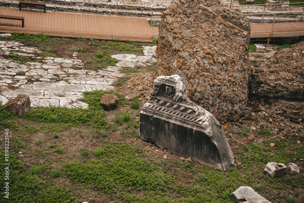 Obraz premium Ancient Roman Ruins with Stone Fragment and Grass at Archaeological Site