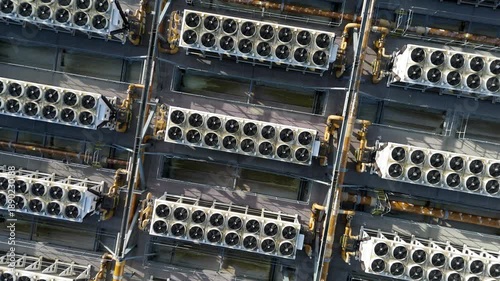 Aerial top down view of symmetrical rows of industrial cooling fans and ventilation systems on a data center rooftop for AI computing infrastructure.