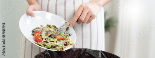 фотографія The housewife is throwing the leftover food from the meal into the bin